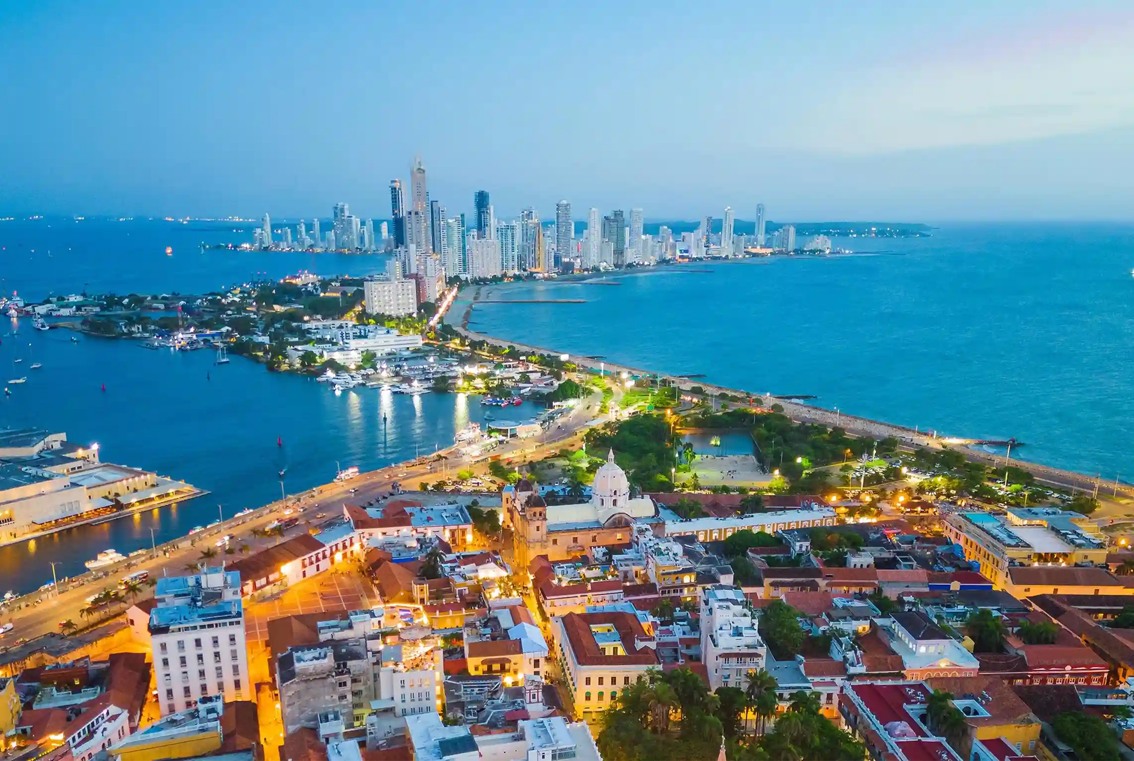 Night aerial view of Cartagena de Indias with illuminated historic center and Bocagrande skyline.
