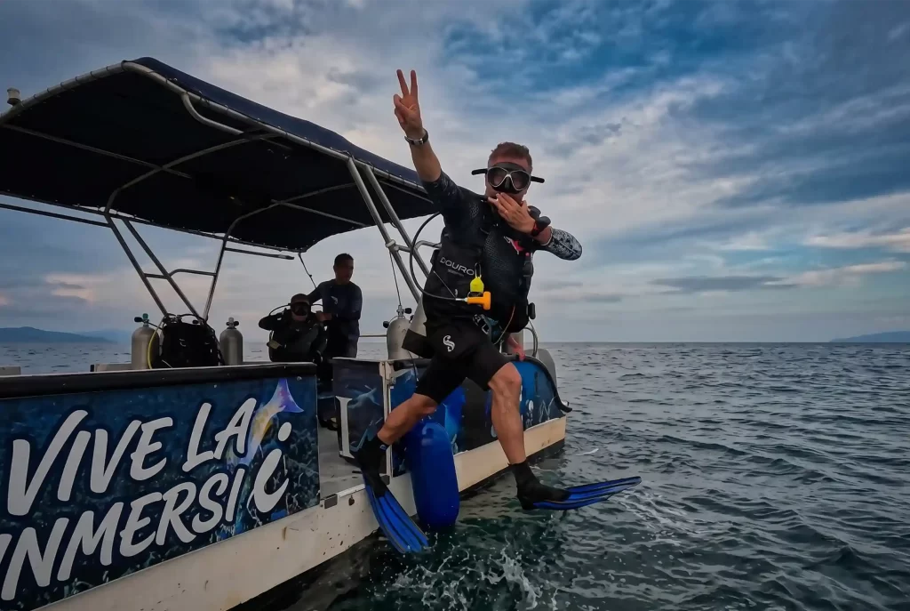 Buzo saltando al mar Caribe desde embarcación de buceo en Cartagena, con equipo completo de inmersión.