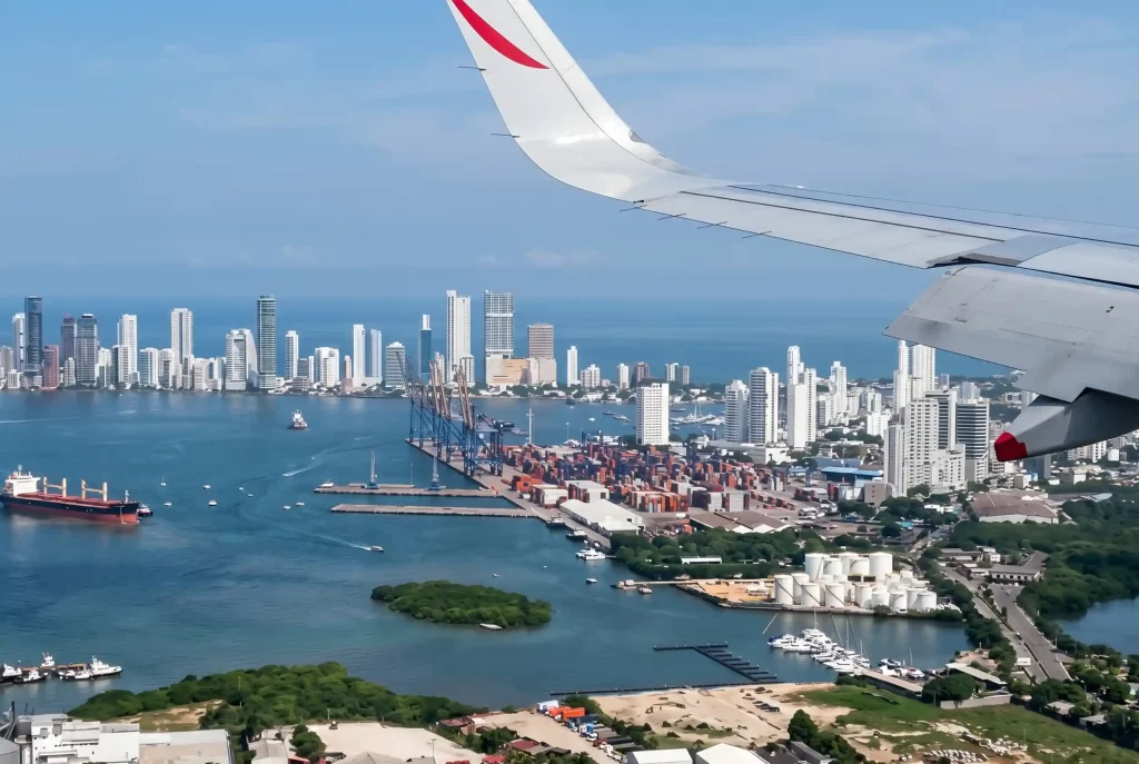 Vista aérea de Cartagena desde ventanilla de avión en aproximación, con skyline de Bocagrande y bahía.