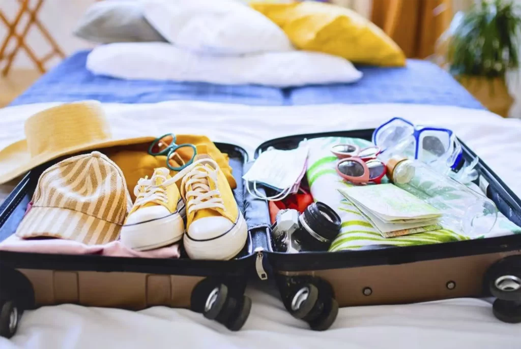Maleta abierta con ropa, sombrero, gafas y accesorios de playa listos para un viaje a Cartagena de Indias.