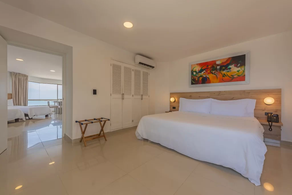 Luxurious premium suite featuring a king bed, modern decor, and adjoining room with ocean view at Hotel Regatta Cartagena.