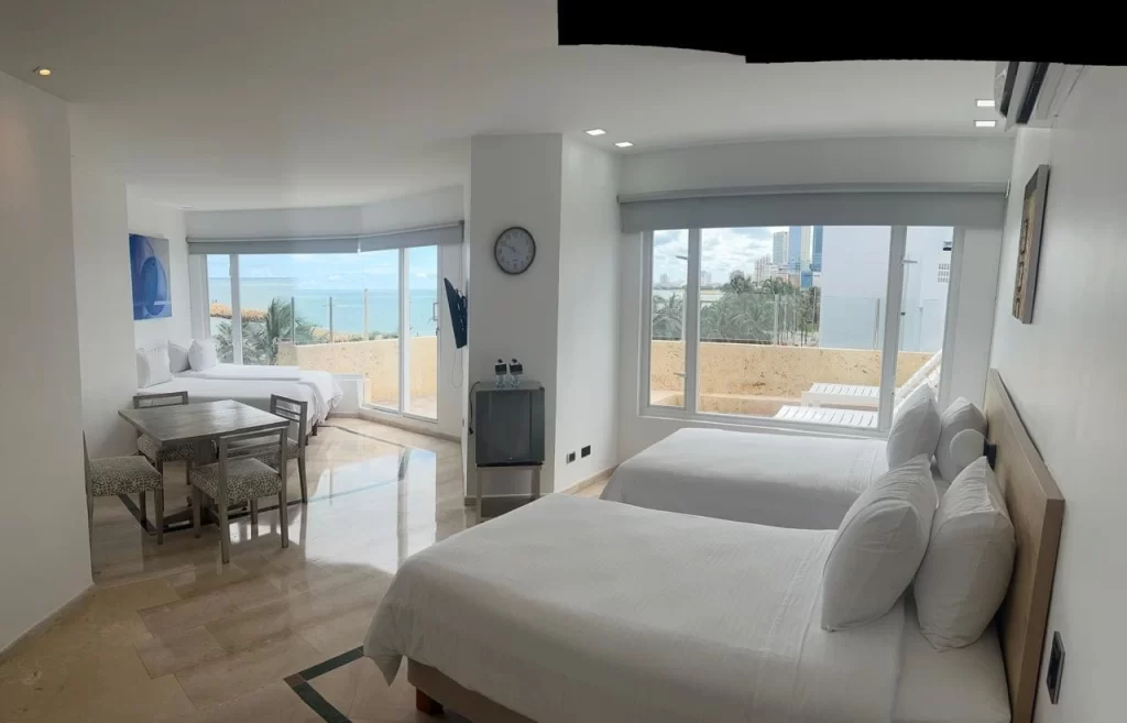Amplia suite séxtuple del Hotel Regatta Cartagena con varias camas, juego de comedor y grandes ventanales luminosos frente al mar