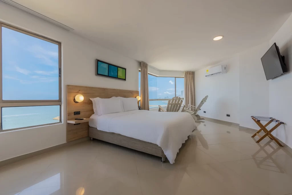 Double bed in a bright superior room featuring large floor-to-ceiling windows with panoramic ocean views at Hotel Regatta Cartagena.