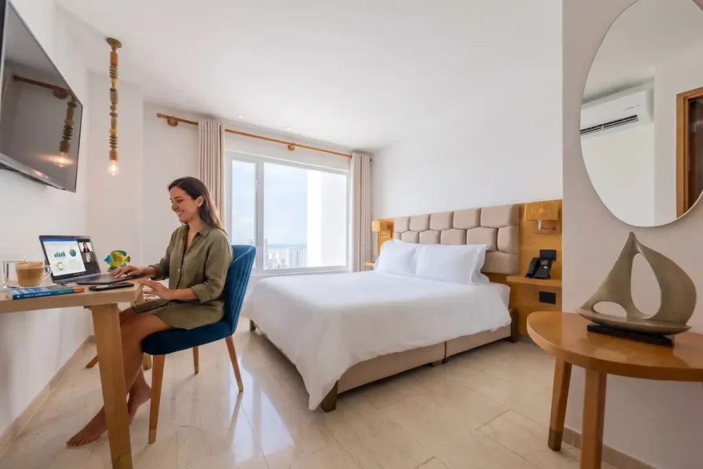 Mujer nómada digital trabajando con su computadora portátil en el escritorio de una habitación de hotel en Cartagena.