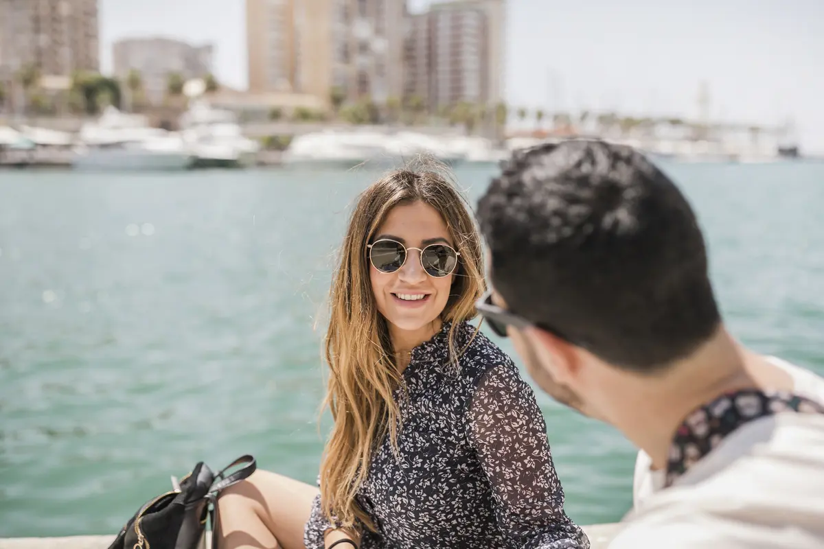 Pareja sonriente con gafas de sol en un paseo en barco por la bahía de Cartagena.