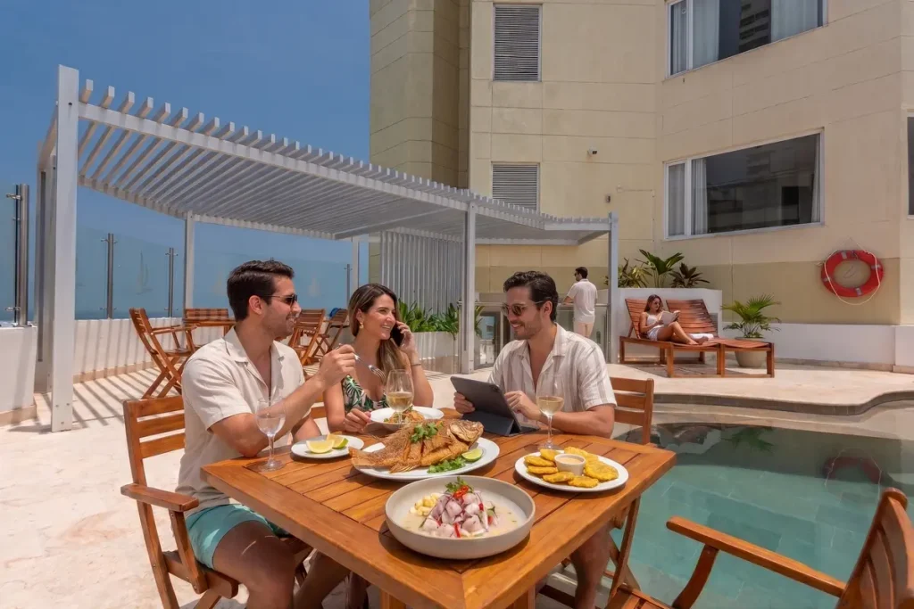 Personas almorzando comida típica caribeña junto a la piscina en una terraza de hotel en Bocagrande, Cartagena.