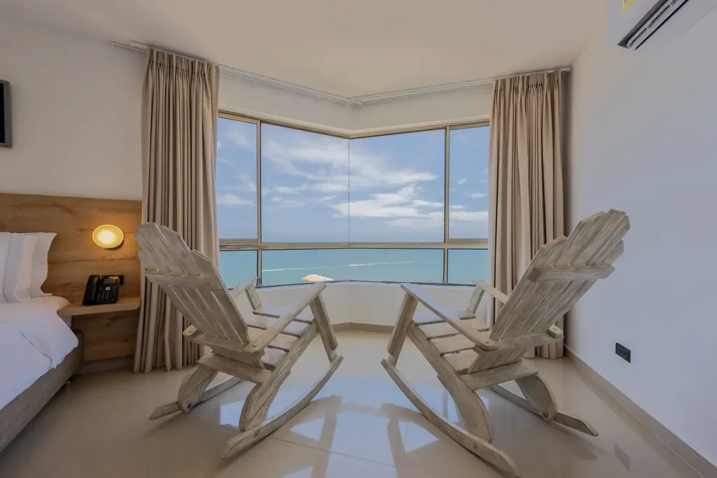 Hotel Regatta room in Bocagrande featuring two wooden rocking chairs facing a floor-to-ceiling ocean view window.