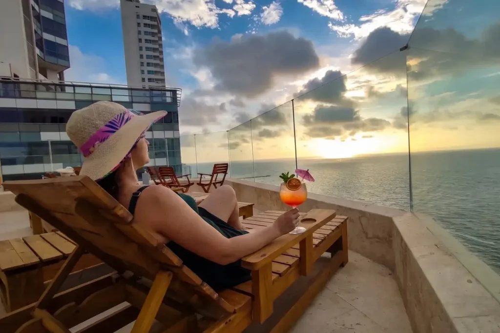 Woman enjoying a cocktail on a rooftop terrace at sunset, perfect for nightlife in Bocagrande, Cartagena.